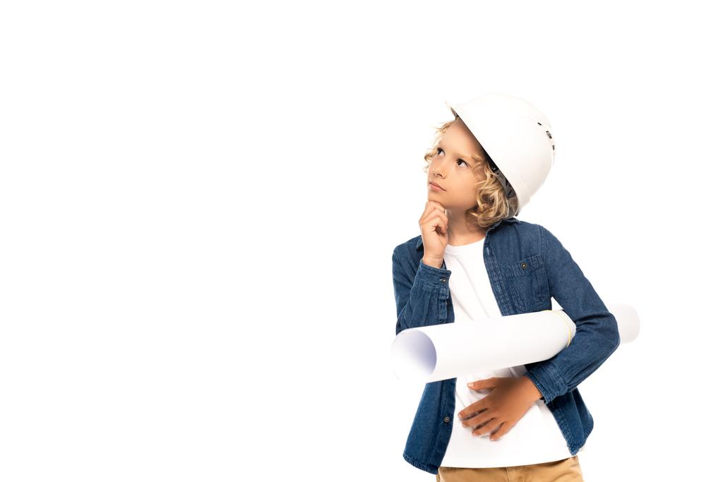 zamyšlený chlapec v bezpečnostní přilbě a kostýmu architekta držícího modrotisk izolovaný na bílém - Fotografie, Obrázek
