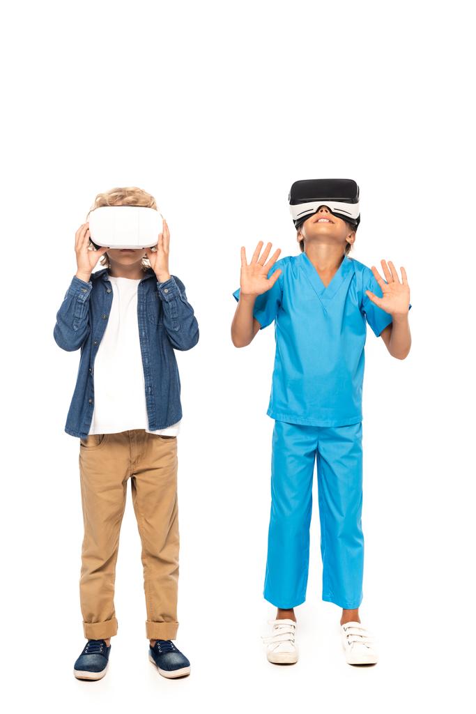 chlapec dotýká virtuální realita sluchátka, zatímco dítě gestikulace izolované na bílém  - Fotografie, Obrázek
