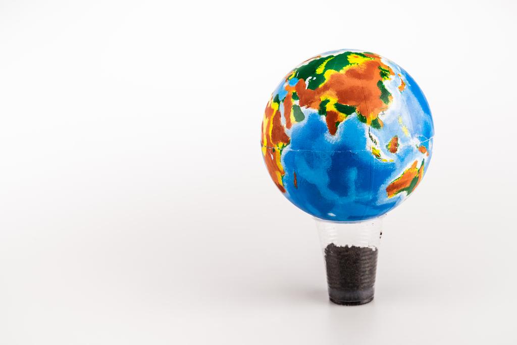 Globus auf Plastikbecher mit Boden auf weißem Hintergrund - Foto, Bild