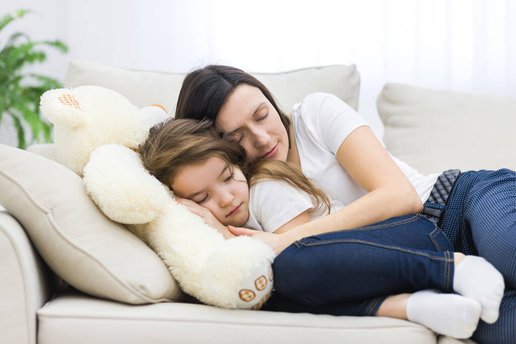 Фото маленькой девочки с мамой, спящей на диване. - Фото, изображение