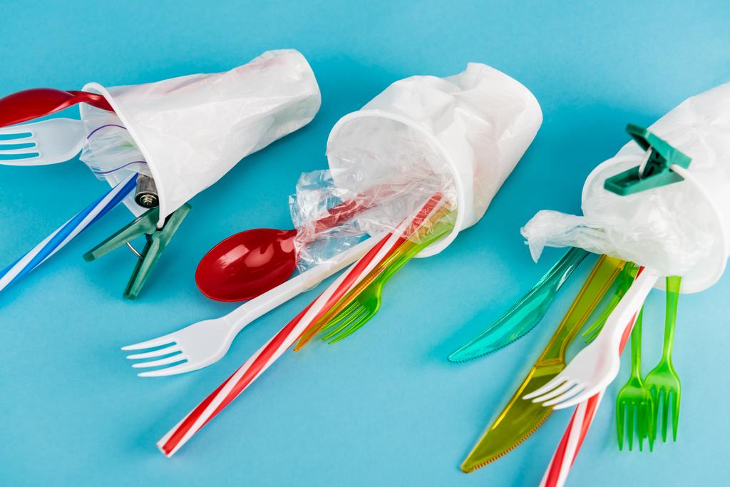 plastic cups with disposable cutlery on blue background - Photo, Image