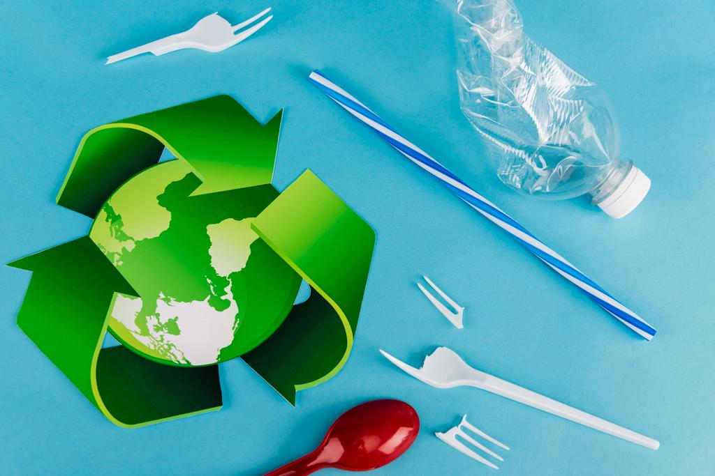 bovenaanzicht van recyclingsymbool bij plastic afval op blauwe achtergrond - Foto, afbeelding