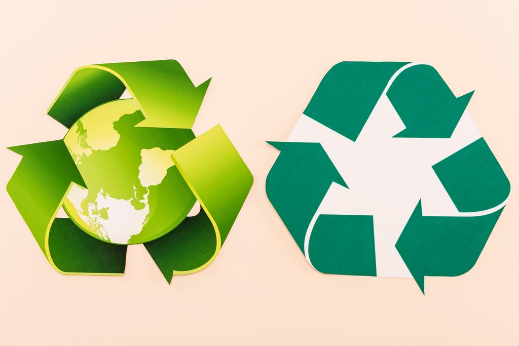 κορυφαία άποψη των πράσινων συμβόλων ανακύκλωσης με τον πλανήτη απομονωμένο σε μπεζ - Φωτογραφία, εικόνα