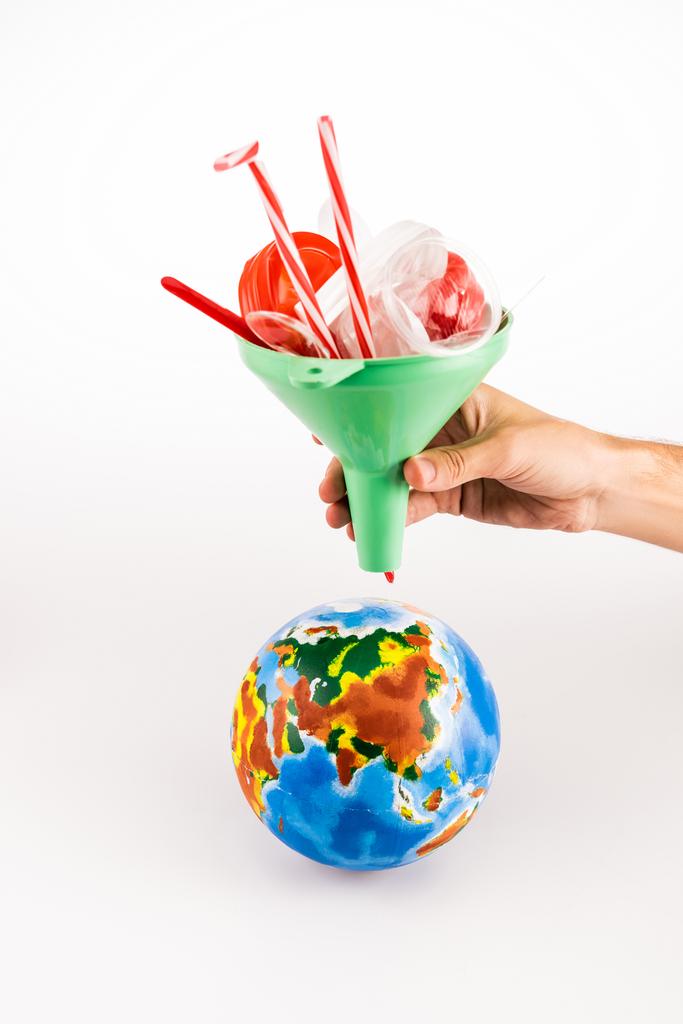cropped view of man holding funnel with plastic above globe on white background - Photo, Image