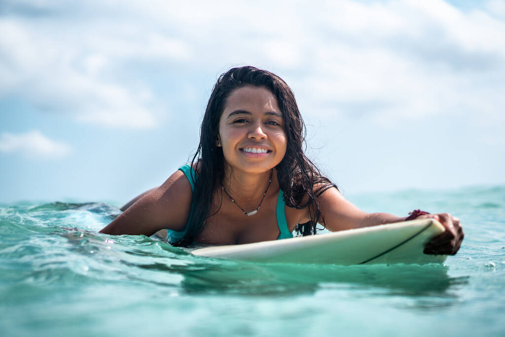 Retrato de surfista menina na prancha de surf branco no oceano azul retratado a partir da água em Bali
 - Foto, Imagem