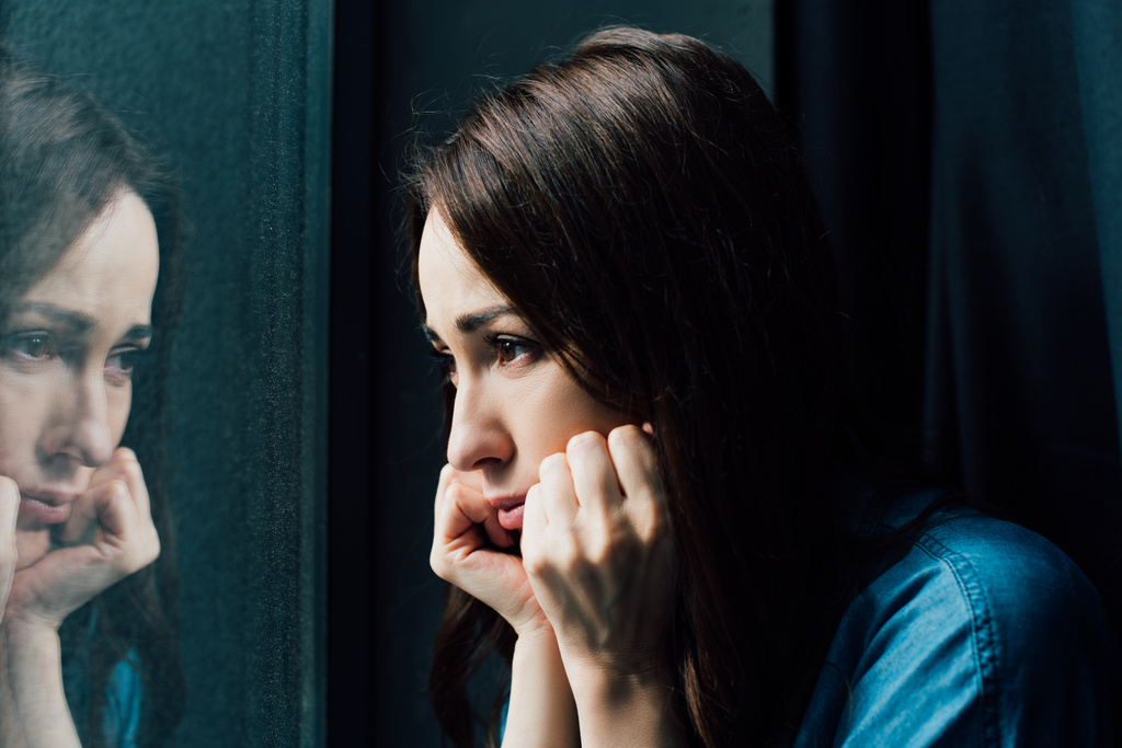 καταθλιπτική μελαχρινή γυναίκα αγγίζοντας το πρόσωπο κοιτάζοντας το παράθυρο  - Φωτογραφία, εικόνα