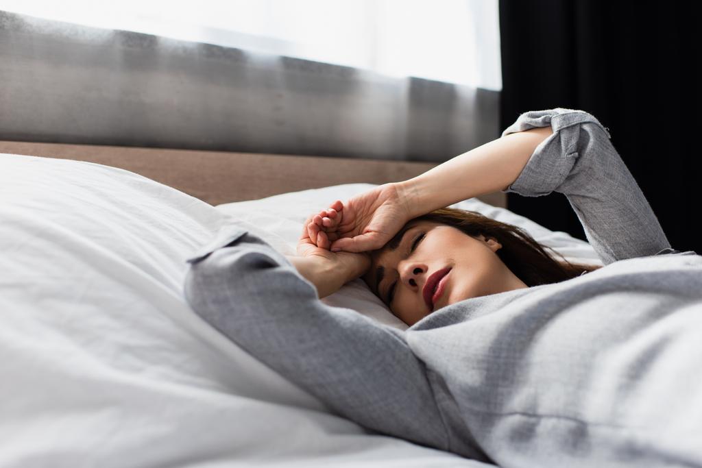 грустная брюнетка, трогательная женщина, лежащая на кровати  - Фото, изображение