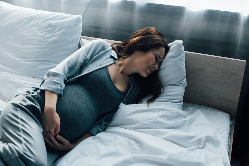 femme enceinte avec les yeux fermés souffrant de douleur au lit  - Photo, image