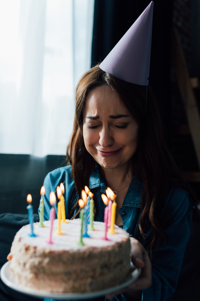 επιλεκτική εστίαση της αναστατωμένος γυναίκα κλαίει, ενώ κρατώντας τούρτα γενεθλίων με κεριά  - Φωτογραφία, εικόνα
