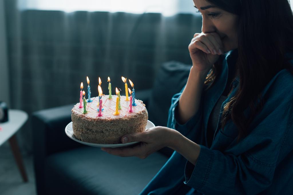 Frustrierte Frau schaut Geburtstagstorte mit Kerzen an  - Foto, Bild