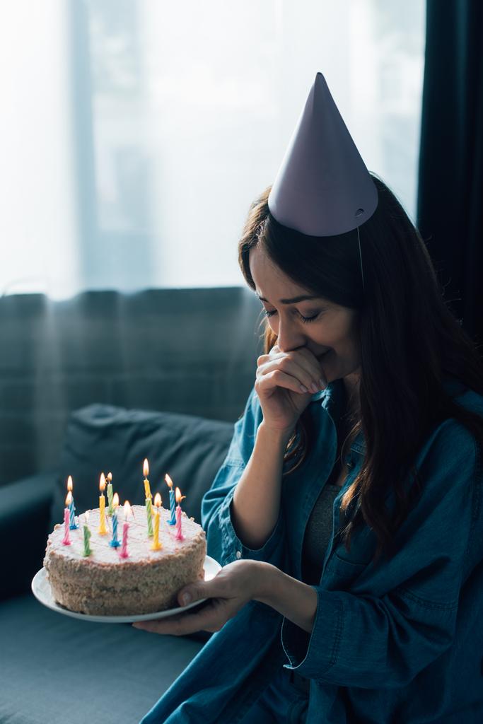 sad woman in party cap crying and holding birthday cake with candles  - Photo, Image