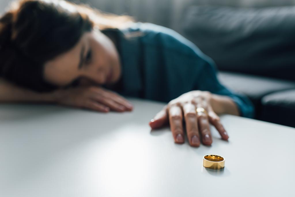 selective focus of upset woman reaching golden ring on coffee table, divorce concept  - Photo, Image