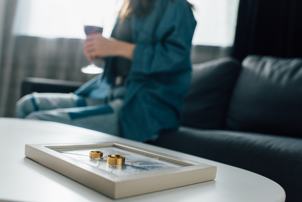 foyer sélectif des anneaux d'or sur cadre photo près de la femme avec verre de vin, concept de divorce  - Photo, image