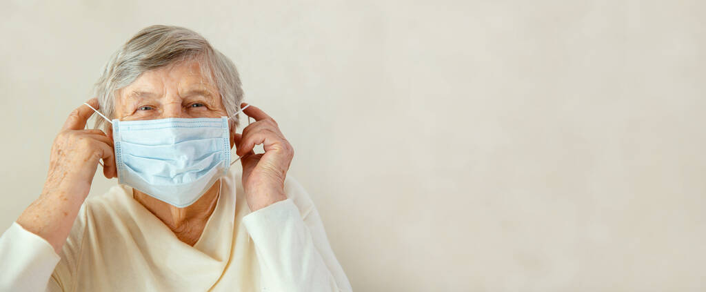 Starší žena si nasadí masku na obličej. Žena s maskou se obává o koronavirus - Fotografie, Obrázek
