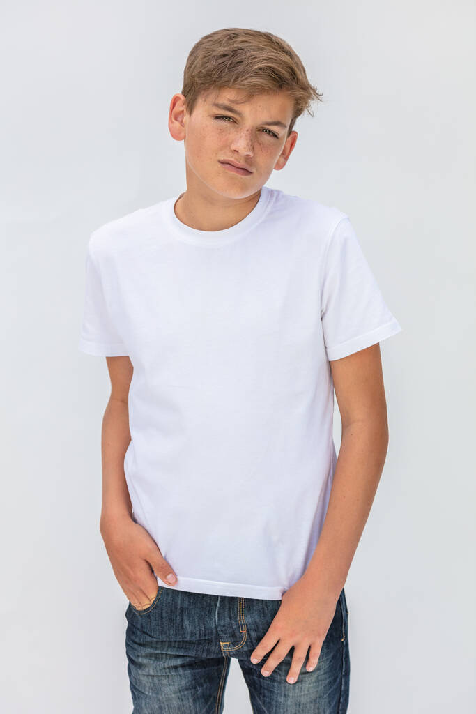 White background studio portrait of a boy teenager teen male child wearing a white t-shirt and blue jeans - Photo, Image