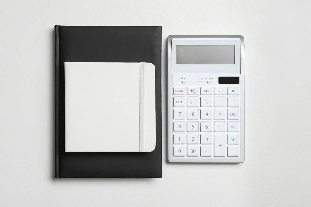 Калькулятор и блокноты на белом фоне, плоский лежал. Налоговый учет - Фото, изображение