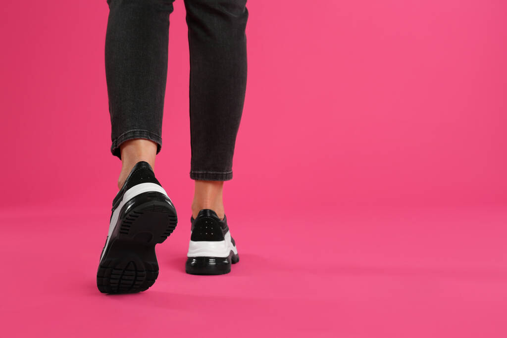 Woman wearing sneakers on pink background, closeup. Space for text - Photo, Image