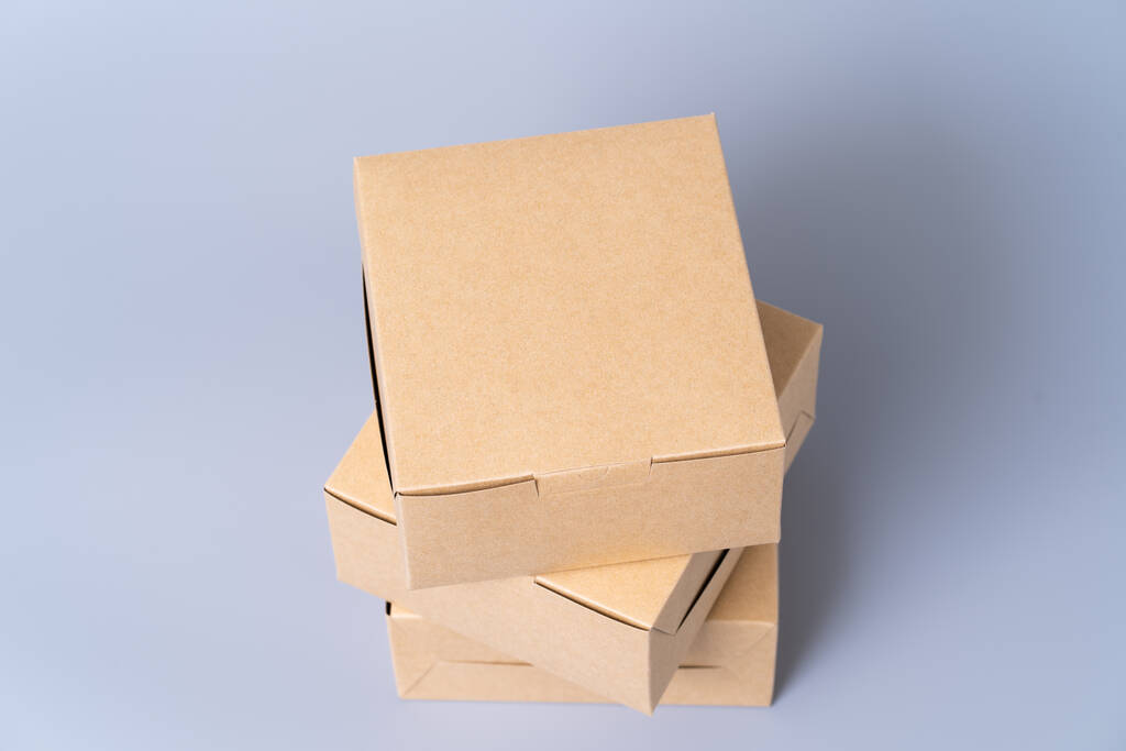 Yiyecek paketi için kahverengi karton kutu. Gri arkaplanda bir karton. - Fotoğraf, Görsel