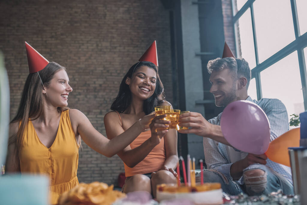 Tři přátelé cinkající sklenice na narozeninové párty - Fotografie, Obrázek