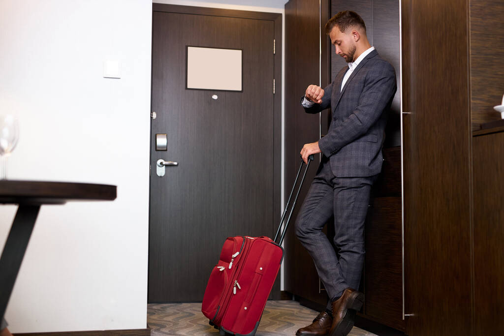 boční pohled na obchodní muž kontrolní čas v hotelu - Fotografie, Obrázek