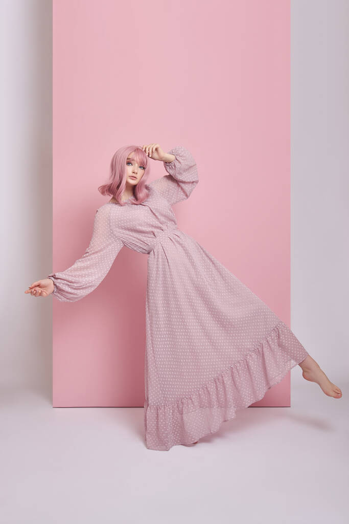 Женщина с розовыми волосами в длинном платье. Портрет девушки с раскрашенными волосами на розовой стене. Идеальная прическа и прическа - Фото, изображение