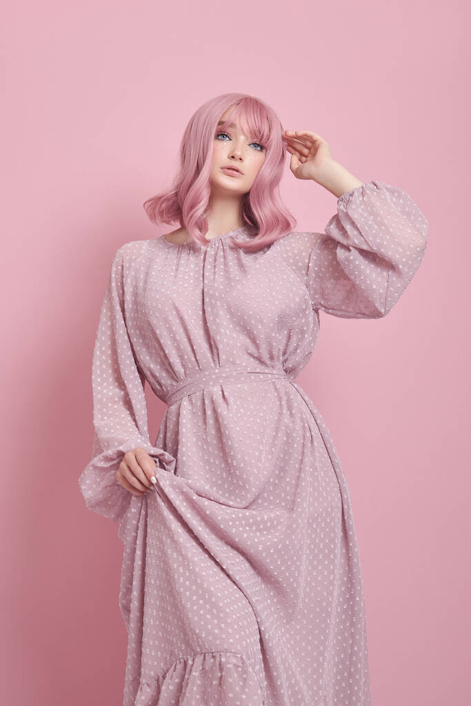 Женщина с розовыми волосами в длинном платье. Портрет девушки с раскрашенными волосами на розовой стене. Идеальная прическа и прическа - Фото, изображение