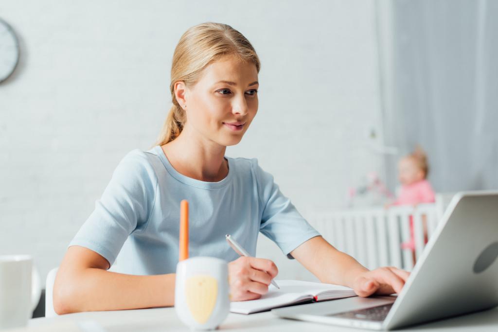 Valikoiva painopiste nainen työskentelee kannettavan tietokoneen ja kannettavan lähellä itkuhälytin pöydällä  - Valokuva, kuva