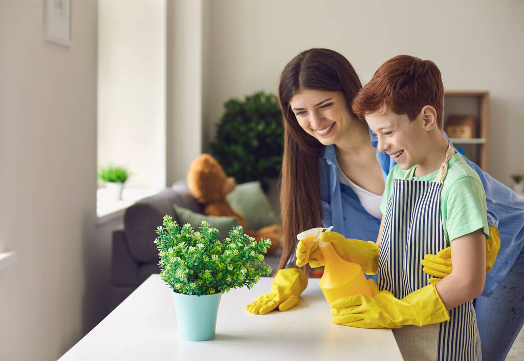 Mother and son having fun while watering houseplant together. - Photo, Image