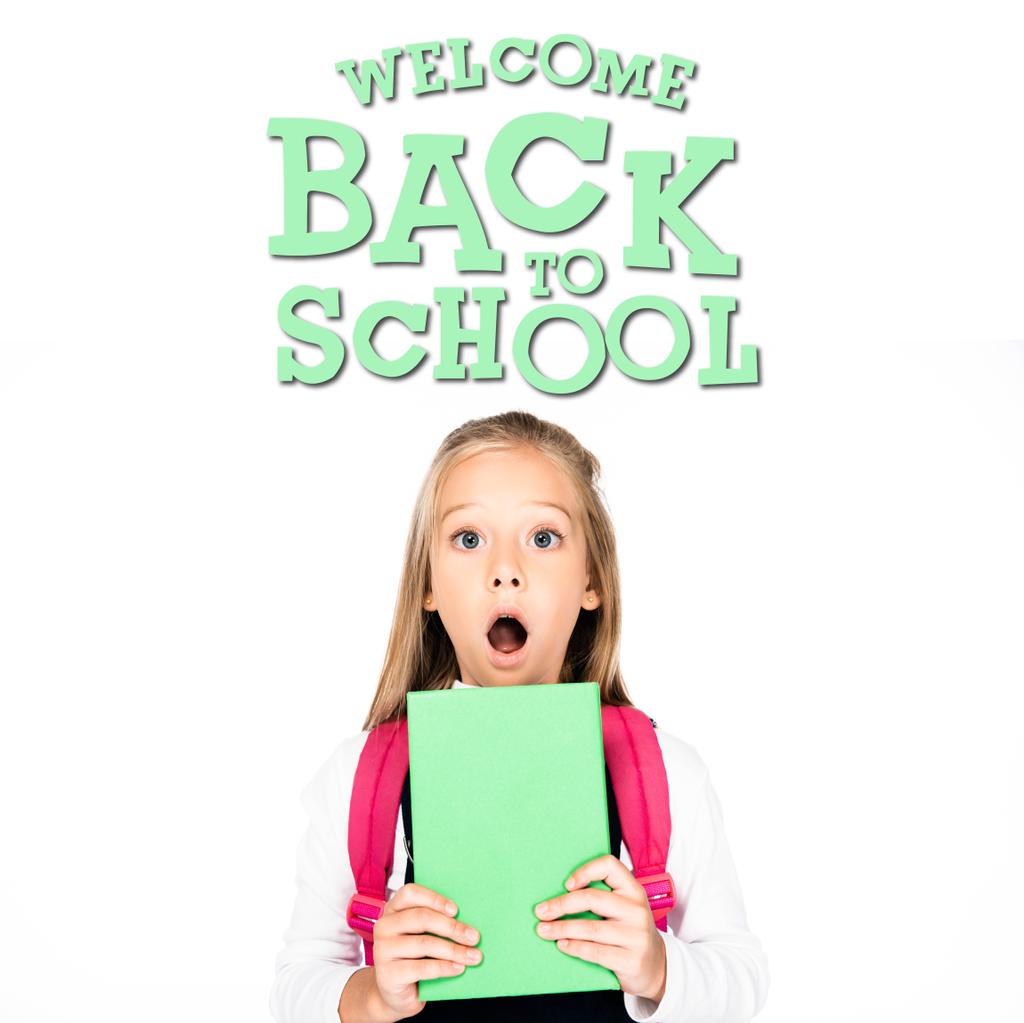 shocked schoolgirl holding book while looking at camera isolated on white, welcome back to school illustration - Photo, Image