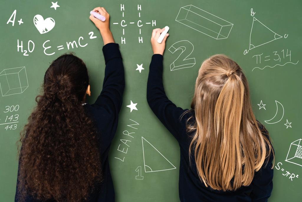 back view of multicultural schoolgirls writing on chalkboard - Photo, Image