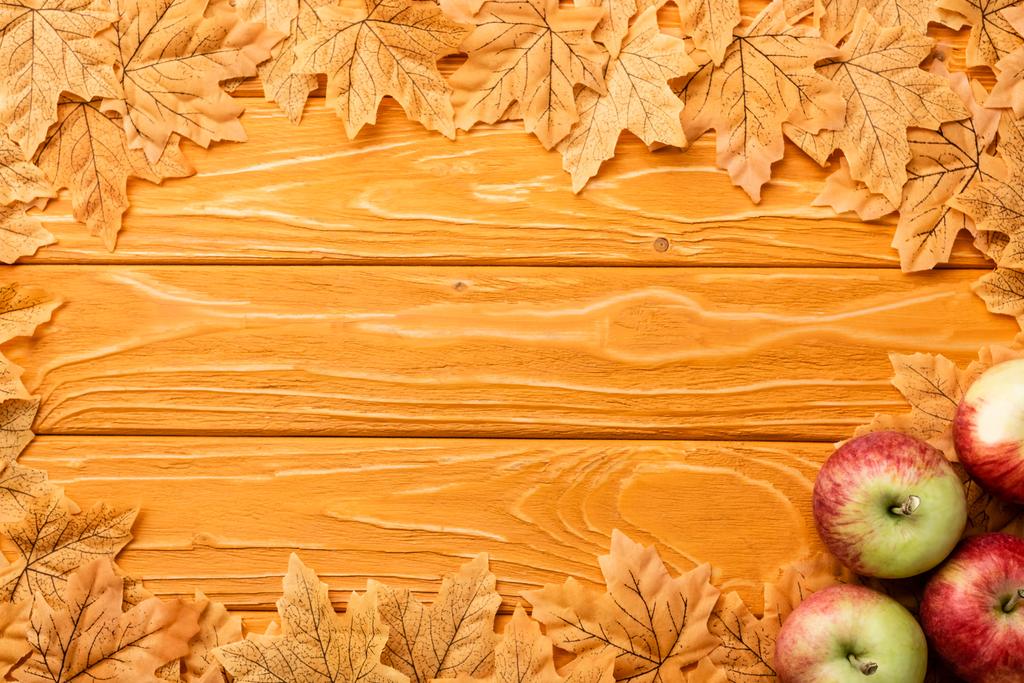 top view of ripe apples and autumnal foliage on wooden background - Photo, Image