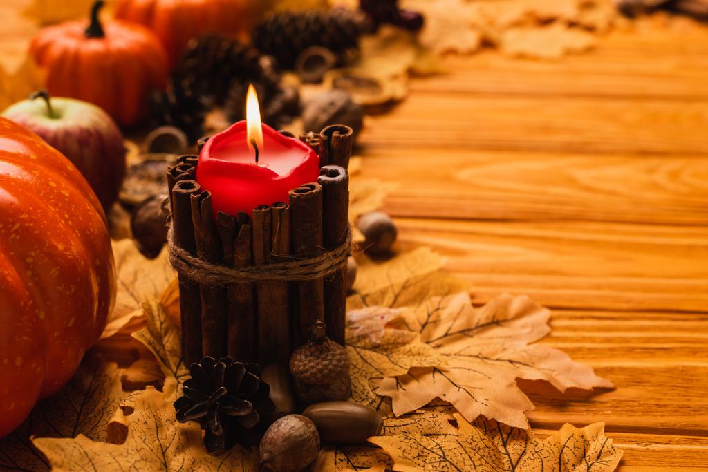 selektiver Brennpunkt der brennenden Kerze mit herbstlicher Dekoration auf Holzgrund - Foto, Bild