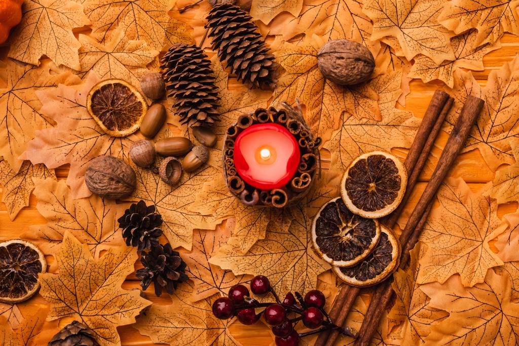 κορυφαία άποψη της καύσης κερί με φθινοπωρινή καφέ διακόσμηση σε χρυσό φύλλωμα - Φωτογραφία, εικόνα