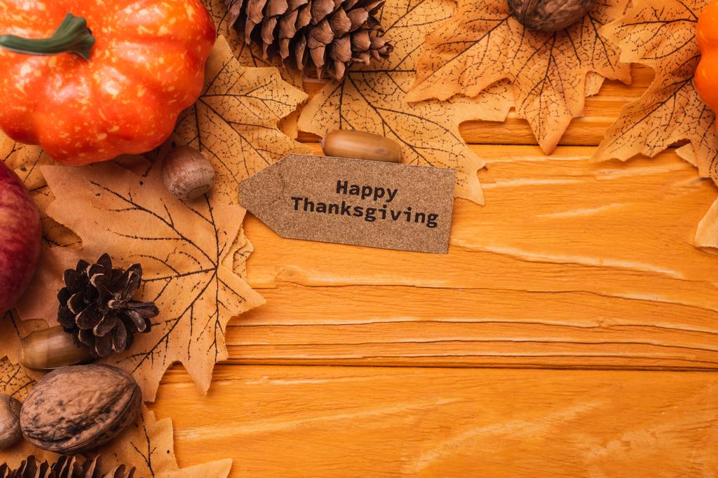 bovenaanzicht van pompoen, herfstdecoratie en gelukkige Thanksgiving kaart op houten achtergrond - Foto, afbeelding