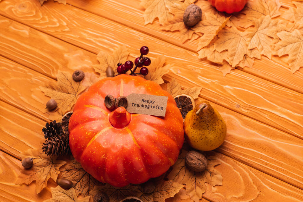 πάνω όψη κολοκύθας με φθινοπωρινή διακόσμηση και χαρούμενη ευχαριστήρια κάρτα σε ξύλινο φόντο - Φωτογραφία, εικόνα