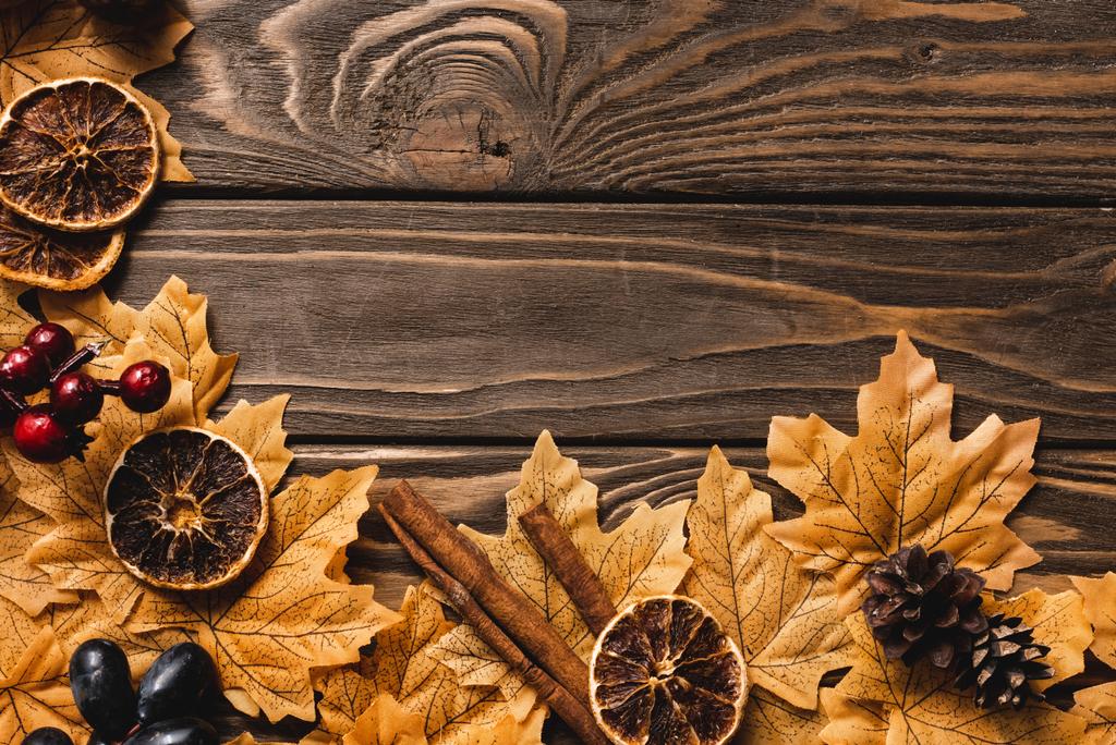 bovenaanzicht van herfstdecoratie en gebladerte op bruine houten ondergrond - Foto, afbeelding