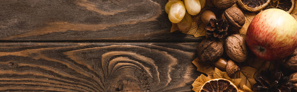 top view of autumnal harvest and foliage on brown wooden background, panoramic shot - Photo, Image