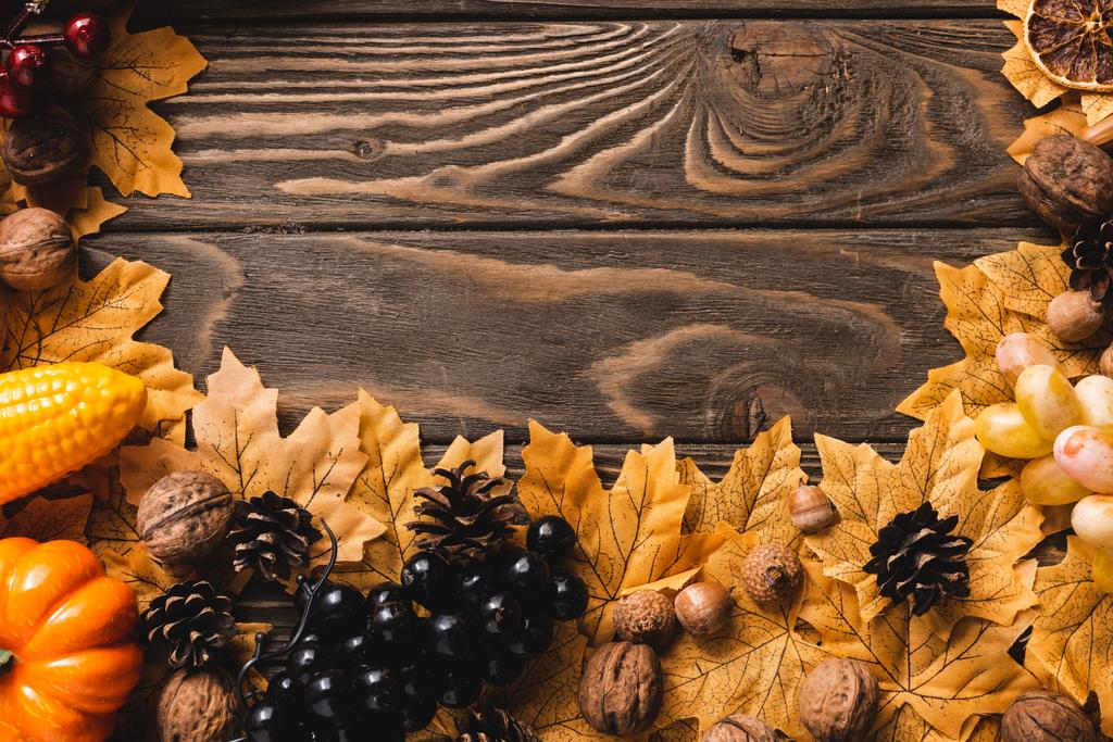 κορυφαία άποψη της φθινοπωρινής συγκομιδής και φύλλωμα σε καφέ ξύλινο φόντο - Φωτογραφία, εικόνα