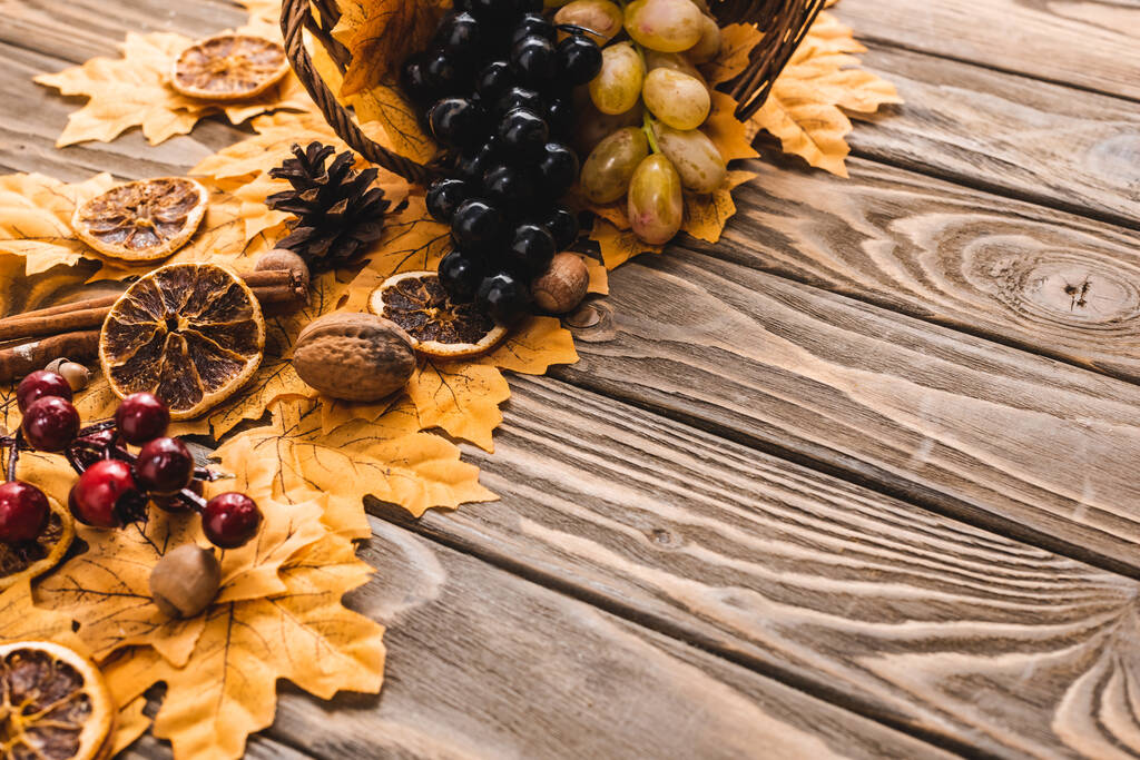 herfst oogst verspreid uit mand op gebladerte op bruine houten achtergrond - Foto, afbeelding
