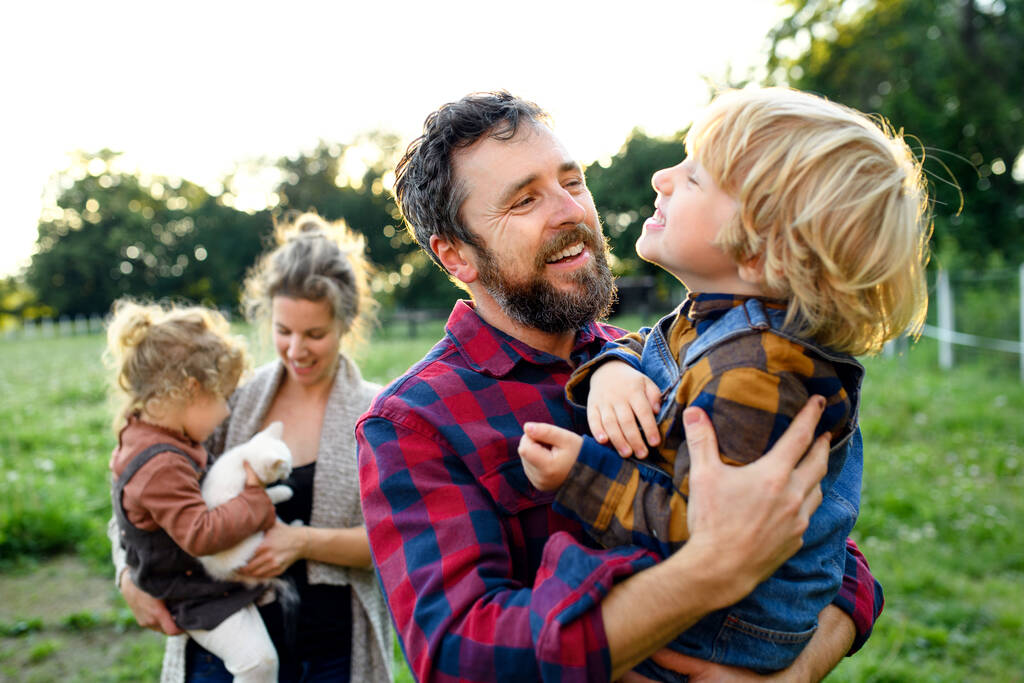 Πορτραίτο οικογένειας με μικρά παιδιά να στέκονται στο αγρόκτημα, ξεκούραση. - Φωτογραφία, εικόνα