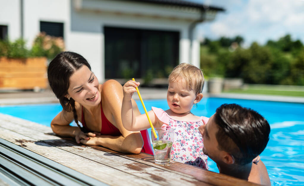 Young family with small daughter in swimming pool outdoors in backyard garden. - Photo, Image