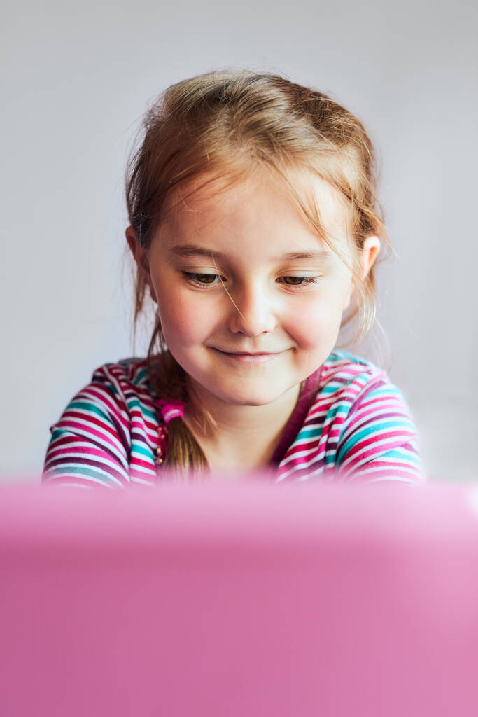 Kislány óvodás tanulás online rejtvények megoldása oktatási játékok hallgatása hangok megtekintése videó táblagépen közben COVID-19 karantén ül az asztalnál a számítógép előtt nézi a képernyőt - Fotó, kép