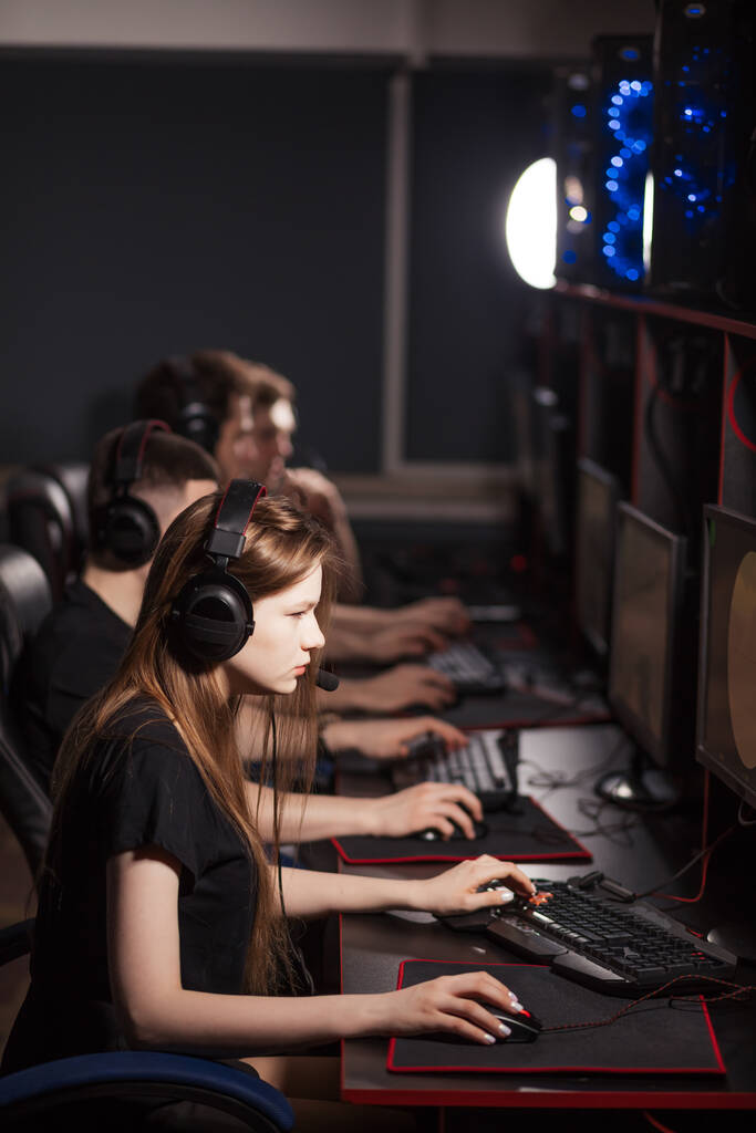 若い女の子はクラブでオンラインビデオゲームで横に座っている他の人と遊ぶ - 写真・画像