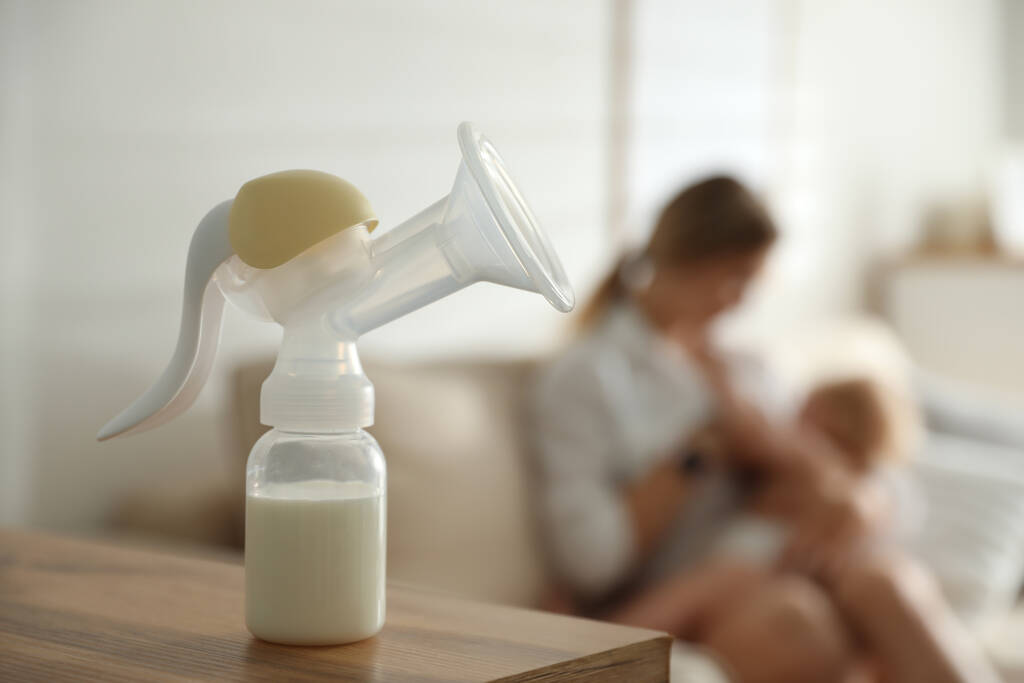 母親は赤ちゃんにミルクを飲ませ乳ポンプに集中する。健康な成長 - 写真・画像