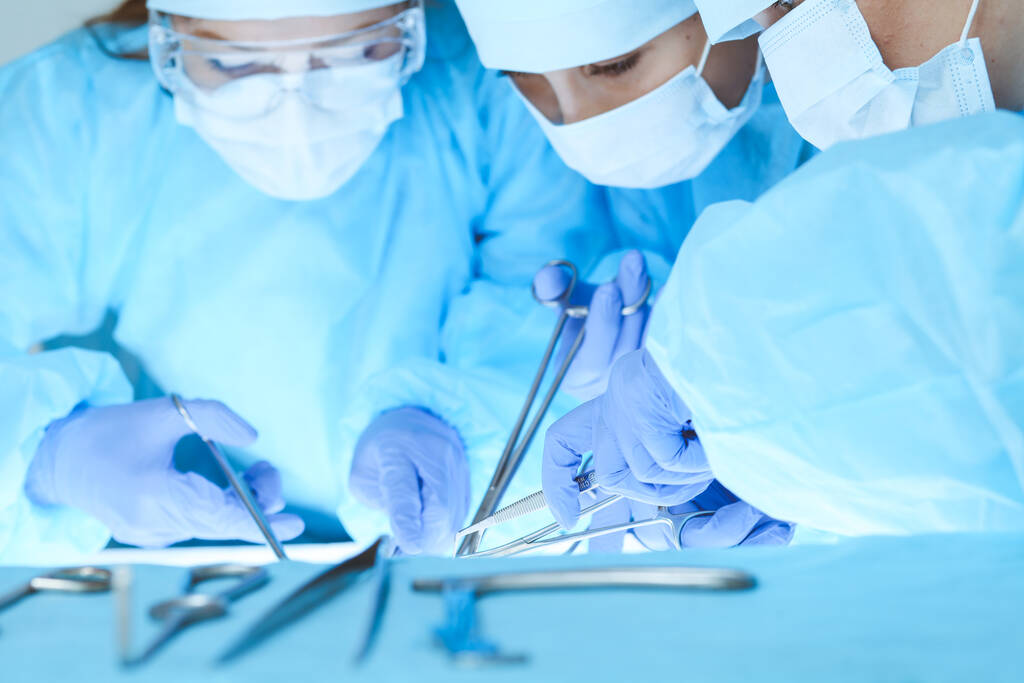 Κοντινό πλάνο της ιατρικής ομάδας που εκτελεί την επιχείρηση. Η ομάδα των χειρουργών στη δουλειά είναι απασχολημένη με τους ασθενείς. Ιατρική, κτηνιατρική ή υγειονομική περίθαλψη και καταστάσεις έκτακτης ανάγκης στο νοσοκομείο - Φωτογραφία, εικόνα