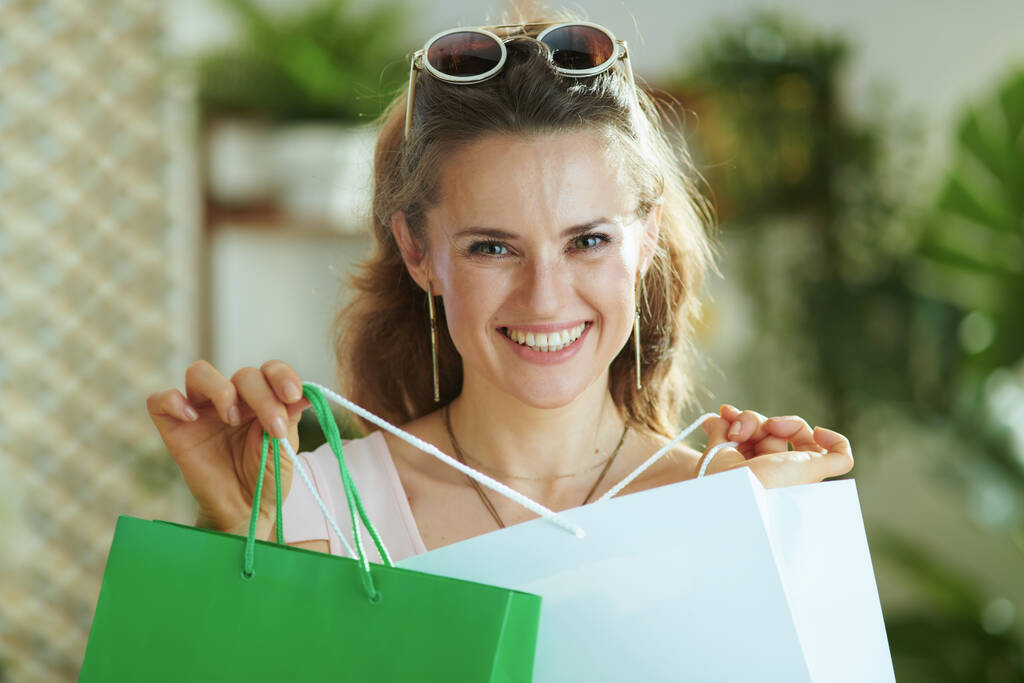 Retrato de mulher moderna feliz comprador em óculos de sol com sacos de compras de papel. - Foto, Imagem
