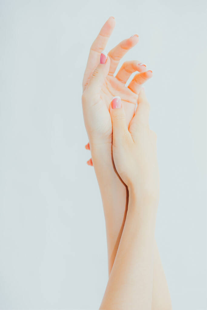 Naisten kädet ranskalainen manikyyri harmaalla pohjalla. Hieronta, voiteen käyttö - Valokuva, kuva