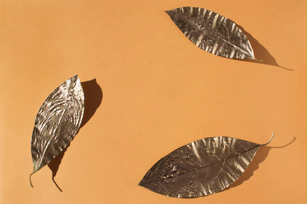 Leaves painted in gold on an orange background. Golden autumn concept. - Photo, Image