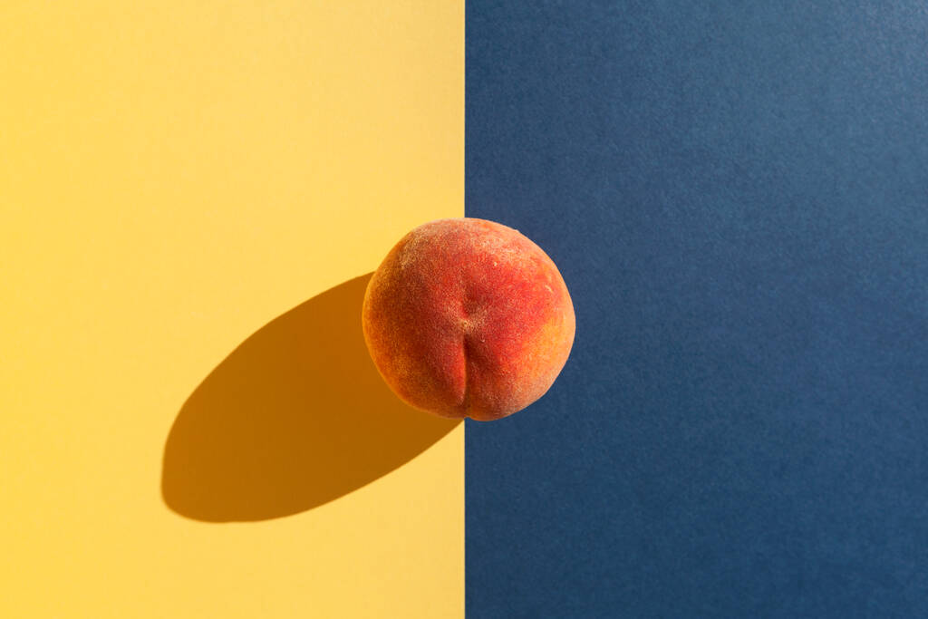 Kypsä mehukas nektariini tai persikka varjossa auringonvalolta kelta-sinisellä pohjalla. - Valokuva, kuva