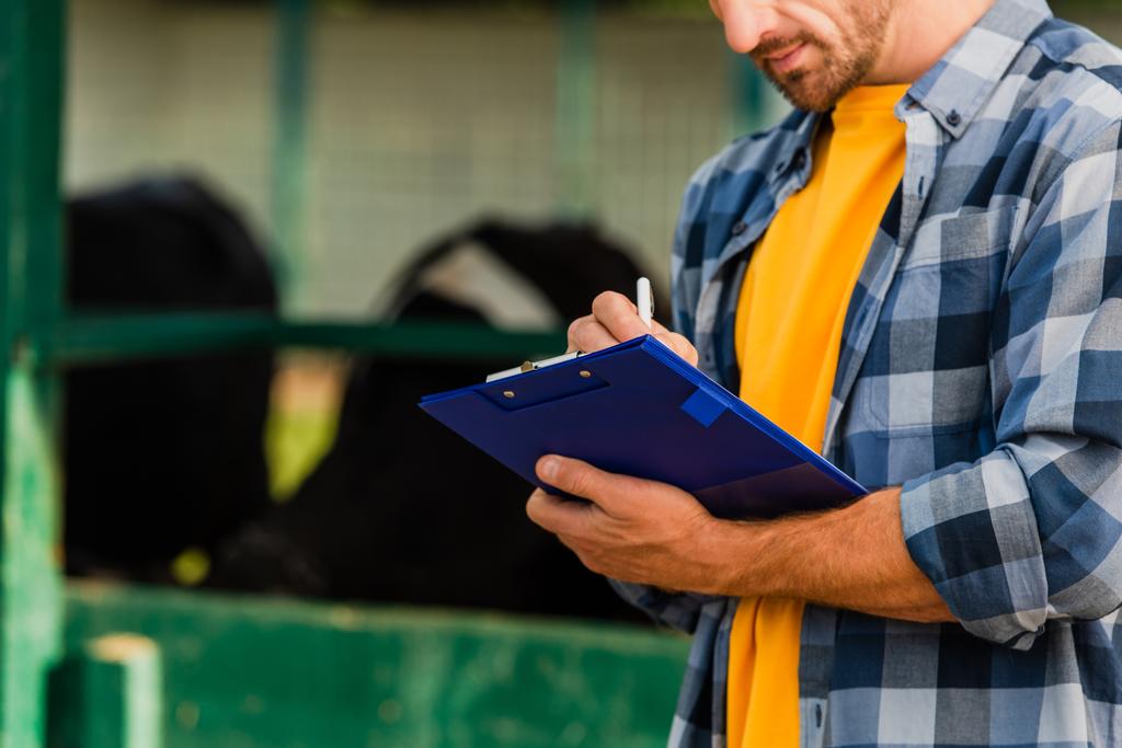 cropped view of farmer in plaid shirt writing on clipboard  - Photo, Image
